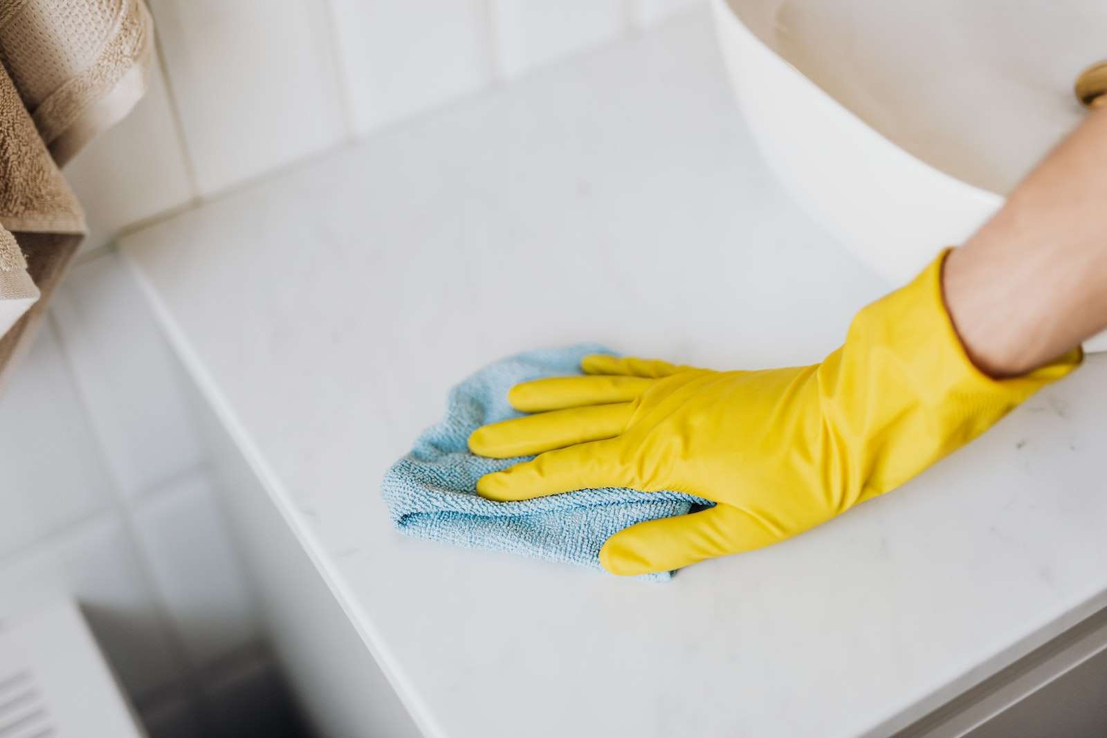 cleaner with gloved hand cleaning the bathroom sink