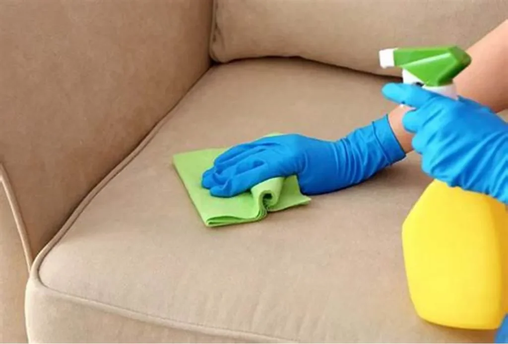 a person spraying cleaning solution and microfiber cloth to clean the sofa